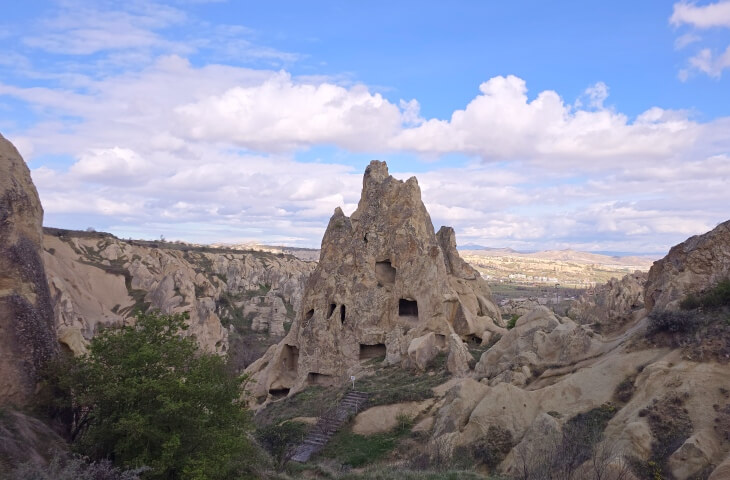 Göreme Açık Hava Müzesi’nde yer alan peri bacası biçimli büyük kaya kütlesi, oyulmuş pencereler ve doğal merdivenlerle birlikte açık bir vadide görülüyor.
